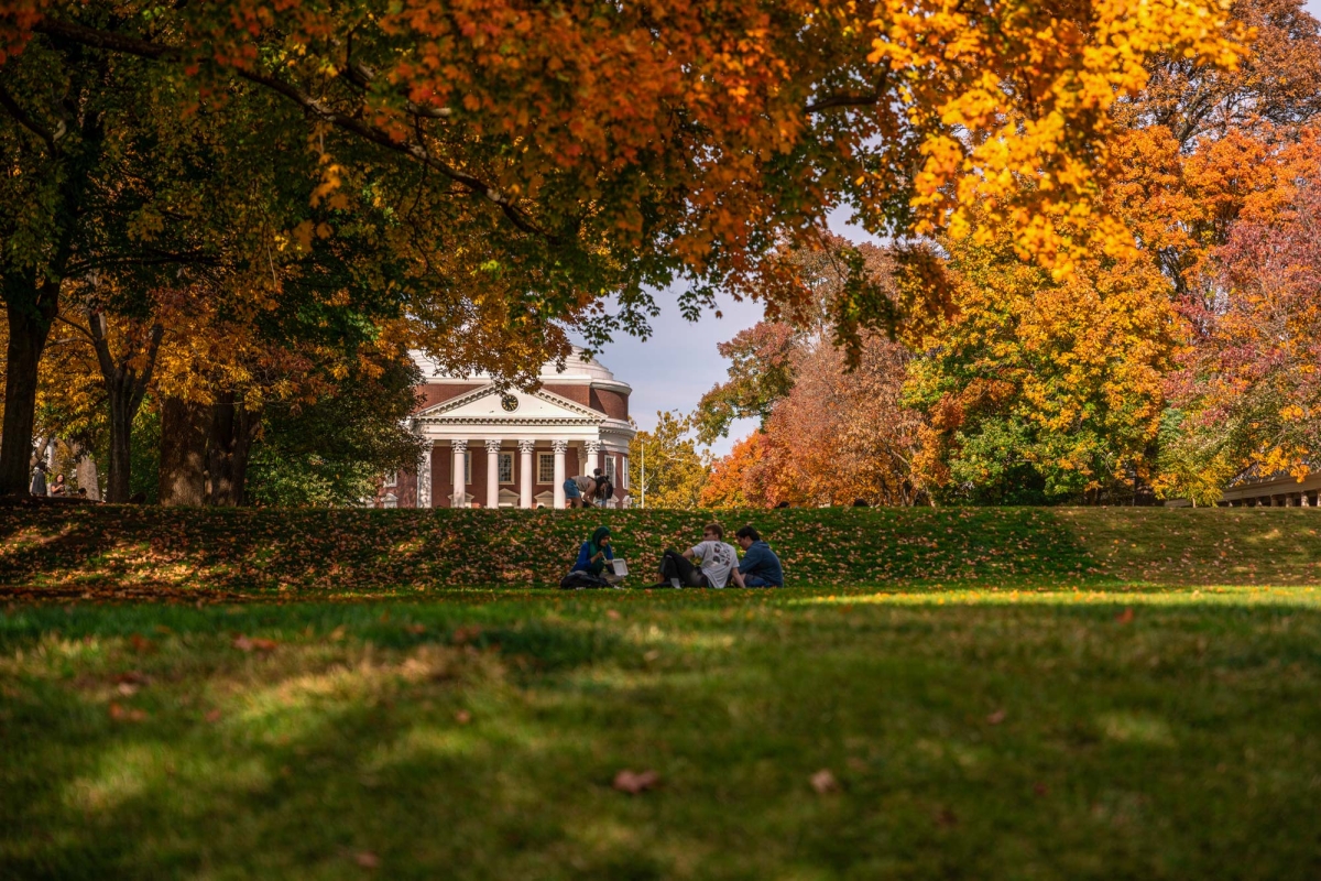 Three students sitting on lawn with the Rotunda in background
