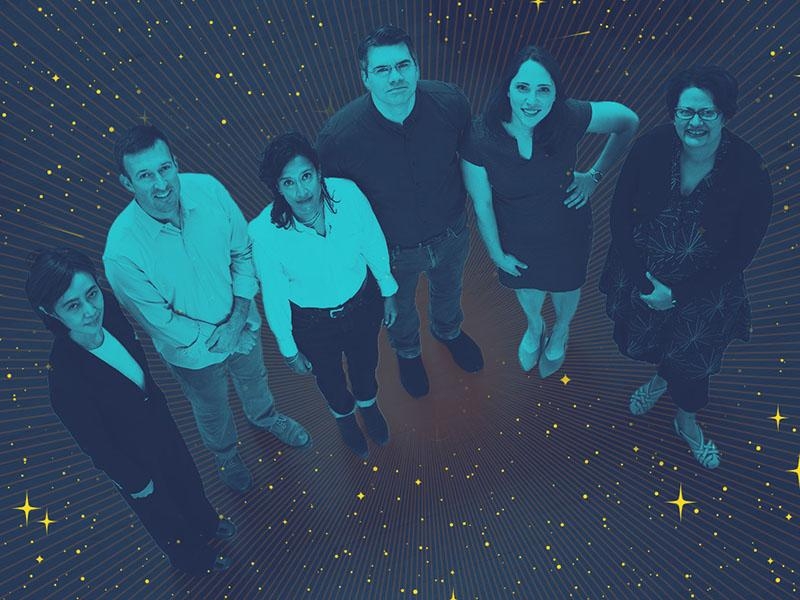 Aerial view of six researcher look up in a dark room with a starry background.