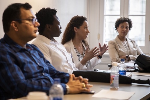 Three faculty members seated at a table listening to a collegue