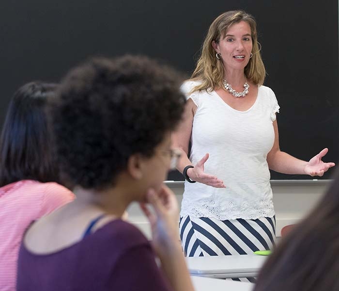 Female professor standing and gesturing in front of students