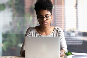 female sitting in front of laptop with the definition of Artificial Intelligence displayed in the background